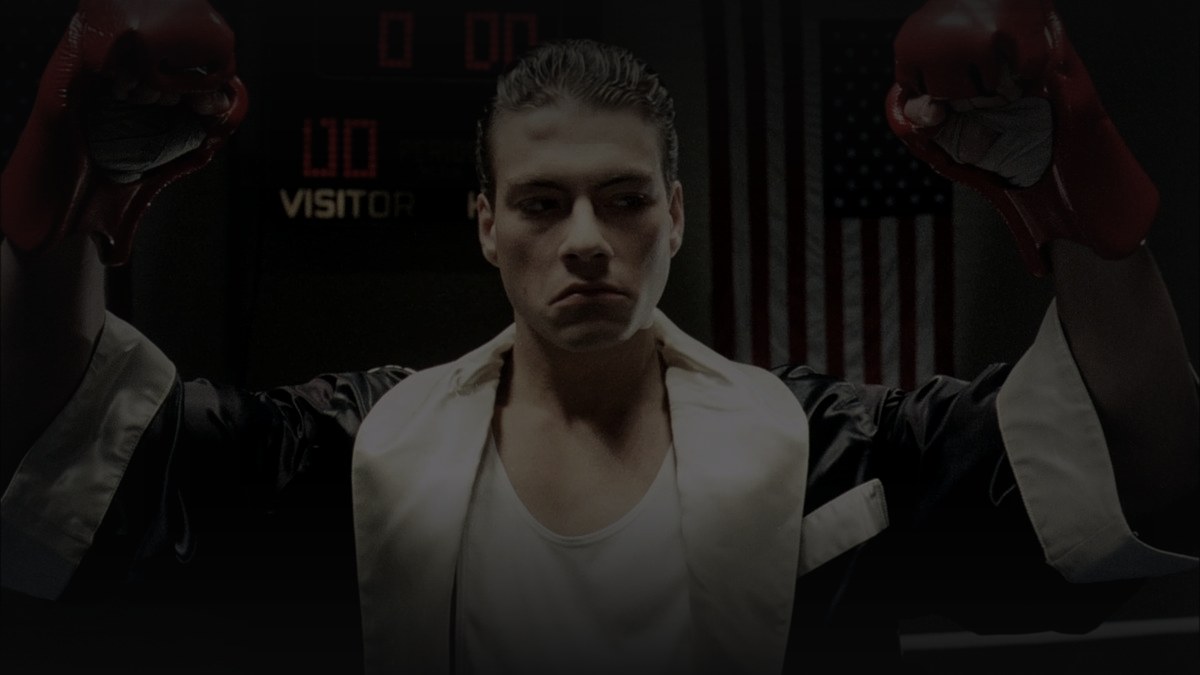 Still from No Retreat, No Surrender (1986) — letterboxd still (1200x675 crop); genuine film frame, van damme in the arena climax, cross-checked against tmdb movie 12721 backdrops (first backdrop rejected as composite). source luma 70.4, pre-darkened 0.80, baked at factor 0.45, 1200x675, on-disk luma 21.1